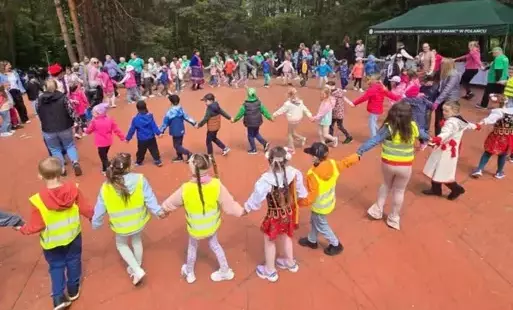 Dzieci na boisku trzymają się za ręce i biorą udział we wspólnych zabawach